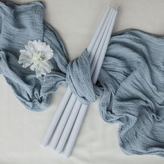 three white candles and a flower on a blue blanket