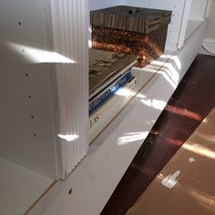 a book is sitting on top of a shelf next to a window with the sun shining through it