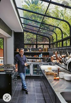 a man standing in a kitchen next to a stove top oven and counter with pots on it