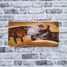 a wooden wall hanging on the side of a brick building with a reflection of trees in it