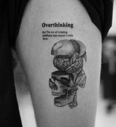 a black and white photo of a skull with an overthiking tattoo on it's thigh