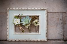 an old frame with flowers in it is hung on the wall by a string and burlap