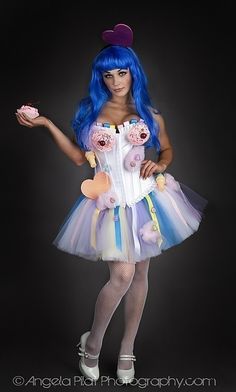 a woman with blue hair is dressed up in a costume and holding a donut