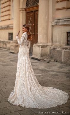 a woman in a white wedding dress standing on the street with her hands behind her head