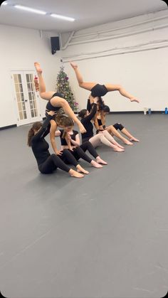 a group of women doing acrobatic tricks on the floor in front of a christmas tree