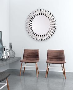 two chairs in front of a mirror on the wall next to a table with vases