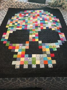 a quilt made to look like an elephant on a bed with black and multicolored squares