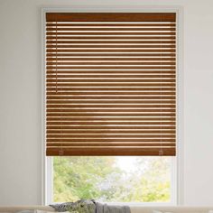 a living room with a couch, window and blinds in the shades that are made out of wood