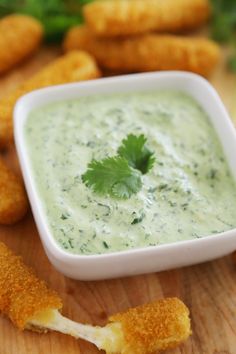 a small bowl filled with dip surrounded by bread sticks and garnished with cilantro