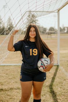 a female soccer player is posing with her ball