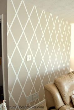 a living room with a brown leather couch and white geometric wallpaper on the walls