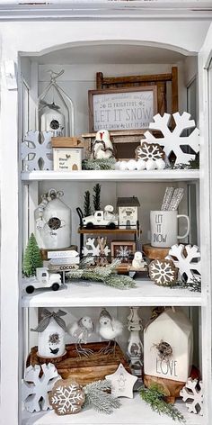 a white shelf filled with christmas decorations and other items on top of it's shelves