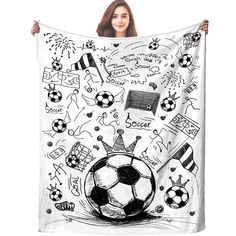 a woman holding up a white blanket with black and white pictures on it, including soccer balls