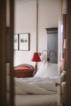 a bed with white sheets and a red lamp