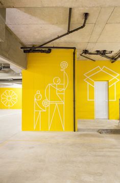 an empty parking garage with yellow walls and white drawings on the wall, along with two open doors