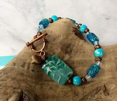 "Turquoise and Aqua beaded bracelet with copper embellishments.  Features 8mm aqua glass beads, blue speckled barrel beads, small diamond cut glass beads, large blue rectangular painted bead, copper spacers, copper heart charm and copper toggle clasp.   A beautiful combination of colors and bead sizes.  It measures 7 1/2\". The bracelet is shipped in a sheer fabric gift bag.  Ideal for gift giving I take pride in my work, and customer satisfaction and feedback is very important to me.  If you have any questions, or requests, please feel free to contact me." Fabric Gift Bag, Glass Beaded Bracelet, Bead Sizes, Aqua Beads, Copper Heart, Aqua Glass, Glass Beaded Bracelets, Fabric Gift Bags, Sheer Fabric