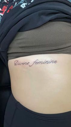 a woman's stomach with the words divine feminine written on her lower back side