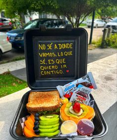 an open lunch box with fruit, sandwiches and condiments on the table outside