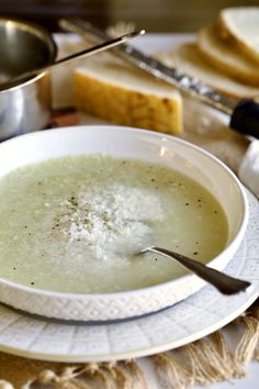 a white bowl filled with soup on top of a table next to bread and butter