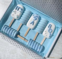 three popsicles in a box with blue frosting and white icing on them