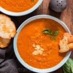 two bowls of soup with bread on the side