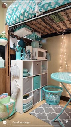 a room with a bunk bed, table and shelves filled with items on top of it