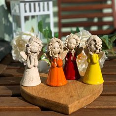 four little angel figurines sitting on top of a wooden table next to flowers