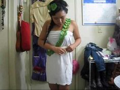 a woman in a white dress looking down at her cell phone while wearing a lei