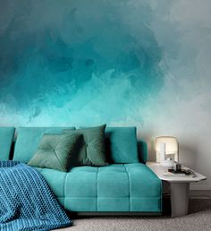 a blue couch sitting in front of a wall with green and blue paint on it