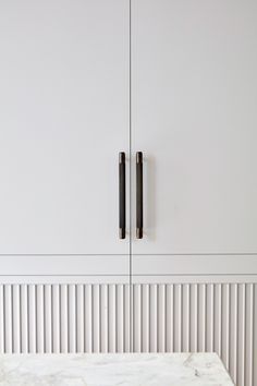 a white cabinet with two black handles and a marble table top in front of it