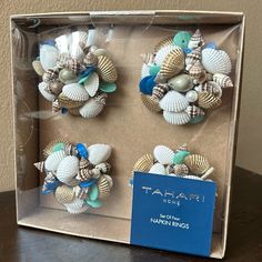 three seashells in a clear box with a blue tag on the front and bottom