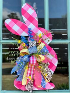 a pink and blue bow hanging from the side of a window