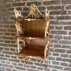 a wooden shelf with deer antlers on it against a brick wall in front of a brick wall