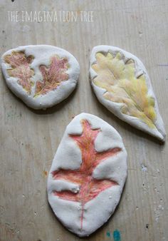 three painted leaves sitting on top of a wooden table