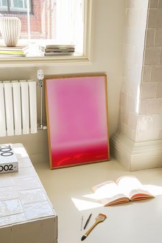 an open book sitting on top of a white table next to a red framed sign