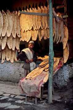 a man standing in front of an open air market with bananas hanging from the ceiling