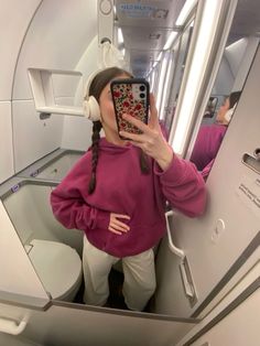 a woman taking a selfie in an airplane with her cell phone and headphones