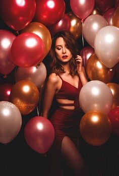 a woman in a red dress surrounded by balloons