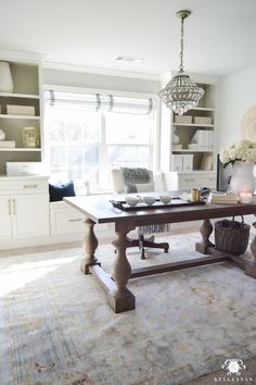 a dining room table and chairs in front of a large window with open shelving