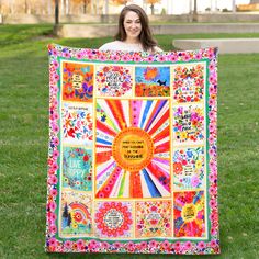 a woman is holding up a colorful quilt