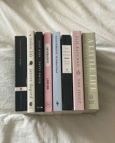 four books are lined up on a bed with the covers pulled back and white sheets