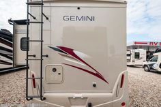 an rv parked on gravel with other vehicles in the background