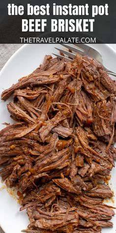 a white plate topped with shredded meat next to a fork