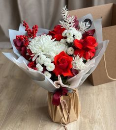 a bouquet of red and white flowers in a paper bag