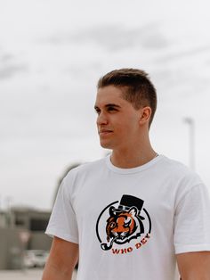 a young man wearing a white shirt with an orange and black tiger on the front