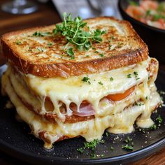 a black plate topped with a sandwich covered in melted cheese and ham, garnished with parsley