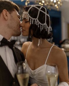 a man in a tuxedo kissing a woman in a white dress with pearls on her head