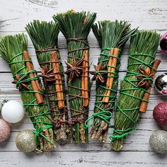 several bundles of grass tied together with twine and christmas ornaments around them on a white wooden surface