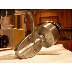 a close up of a metal object on a white table cloth with wood cabinets in the background