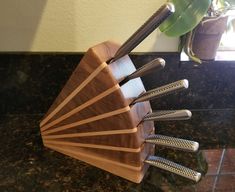 a wooden holder with five knives and four forks in it on a marble counter top